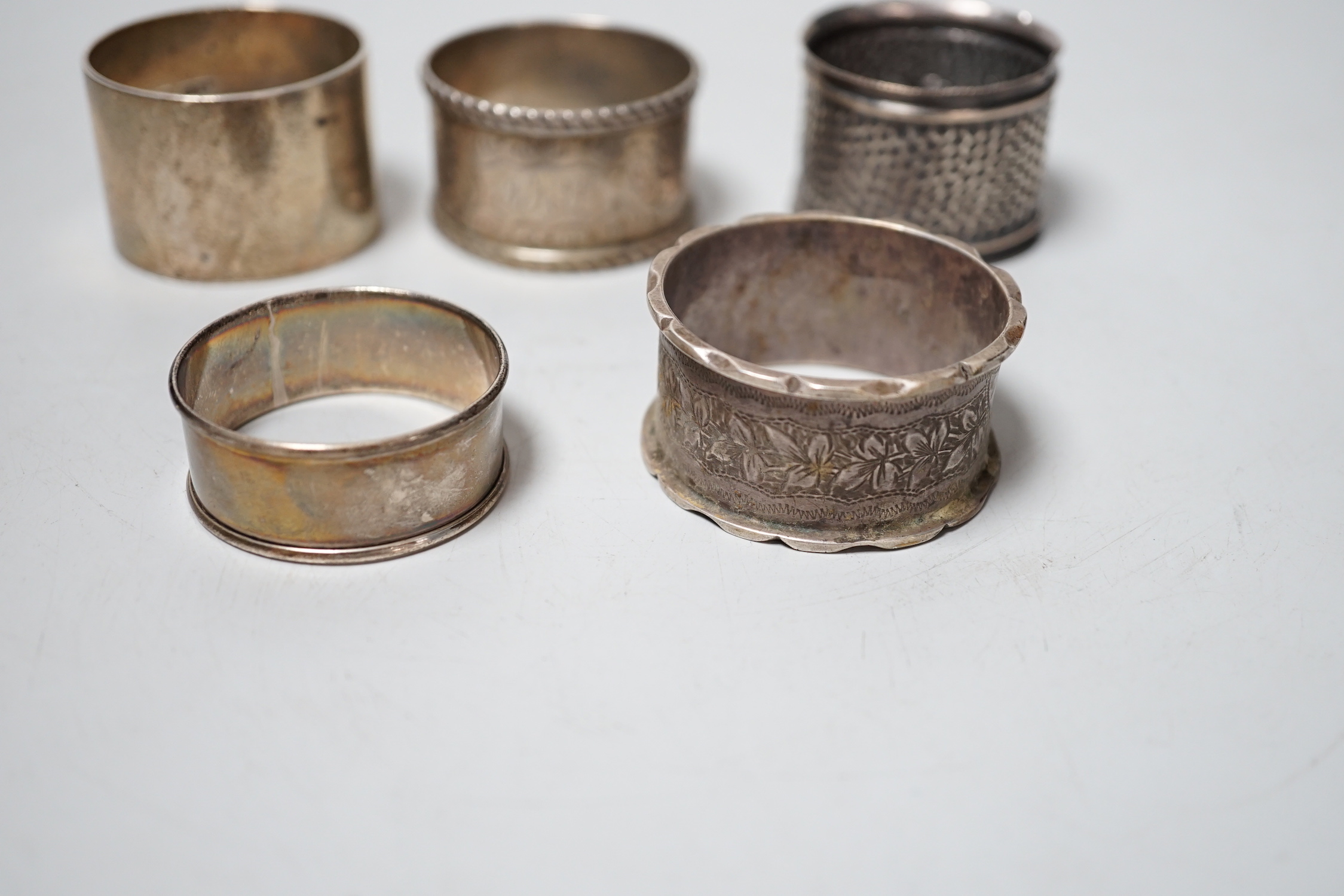 Five assorted silver napkin rings.